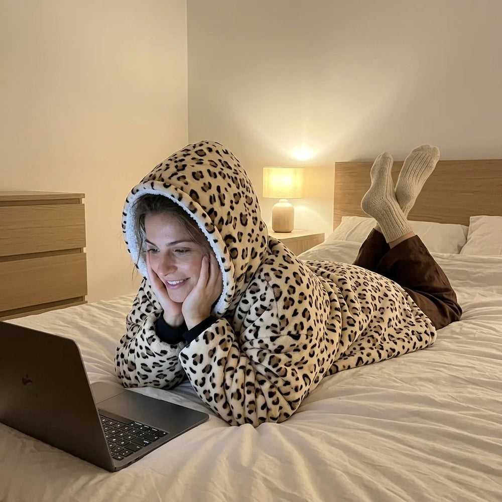 Woman in the Cream Leopard blanket hoodie watching a series on her laptop in bed