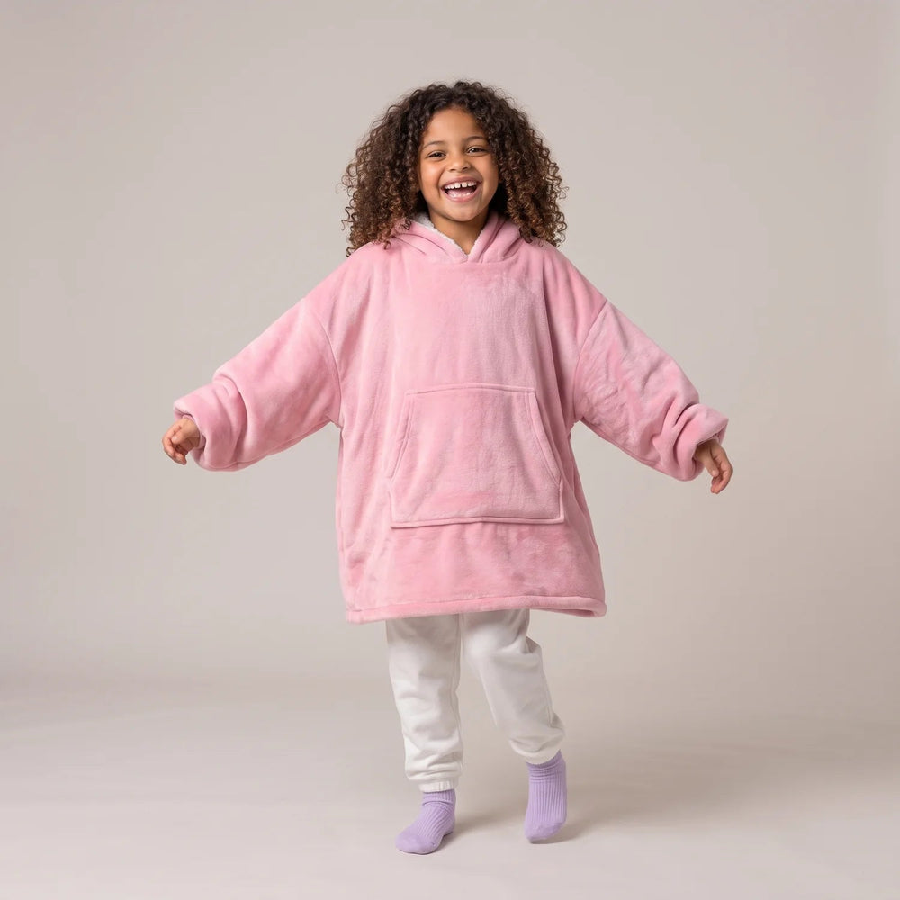 Child wearing the Light Pink Kids blanket hoodie, studio photo