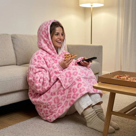 Woman in the Pink Leopard blanket hoodie having pizza on the living-room floor, knees tucked in