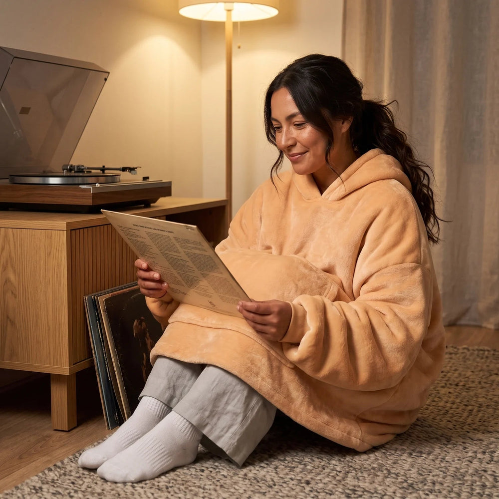 Woman in the Apricot blanket hoodie looking through vinyl records on the living-room floor in the evening